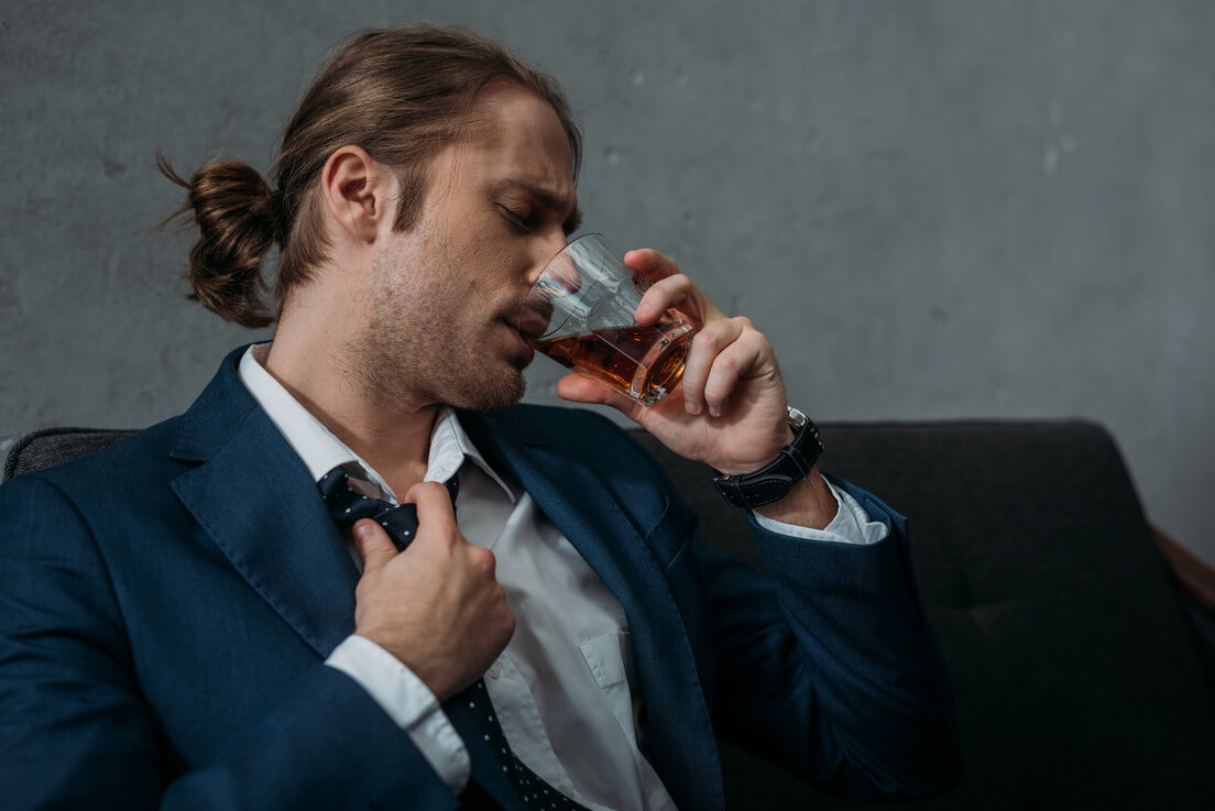 a man drinking whiskey on a couch
