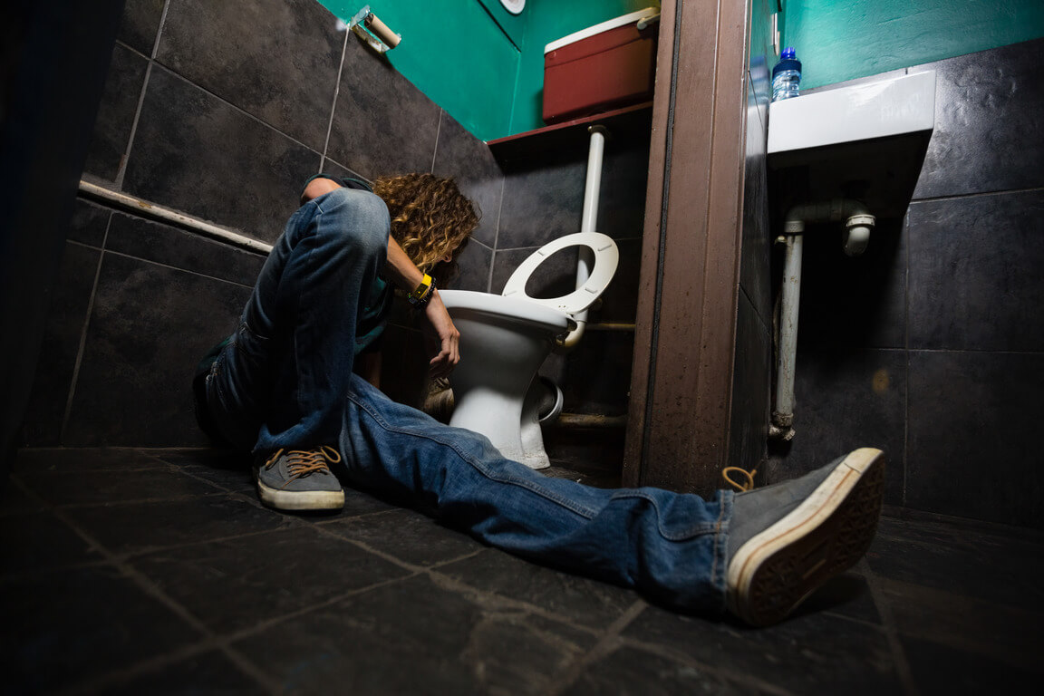 a guy vomiting in the toilet due to alcohol detoxing