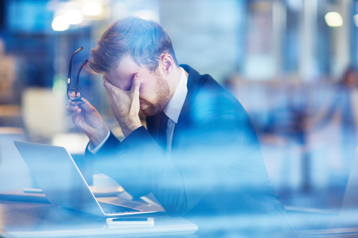 a man who is a heroin user is holding his head while in the office